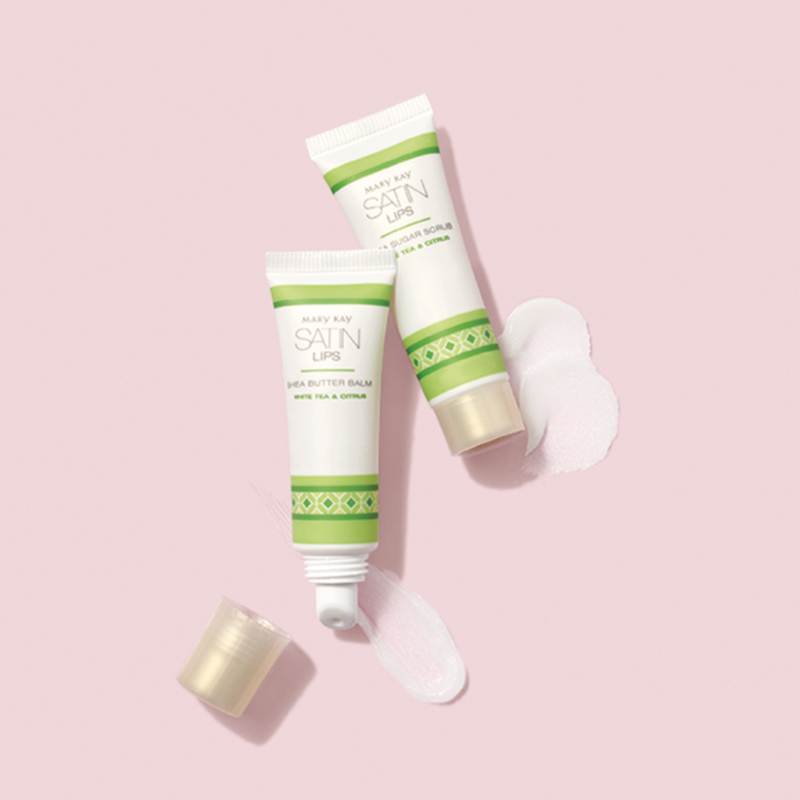 White Tea & Citrus Satin Lips Shea Butter Balm y Shea Sugar Scrub con muestras de producto contra un fondo rosa claro